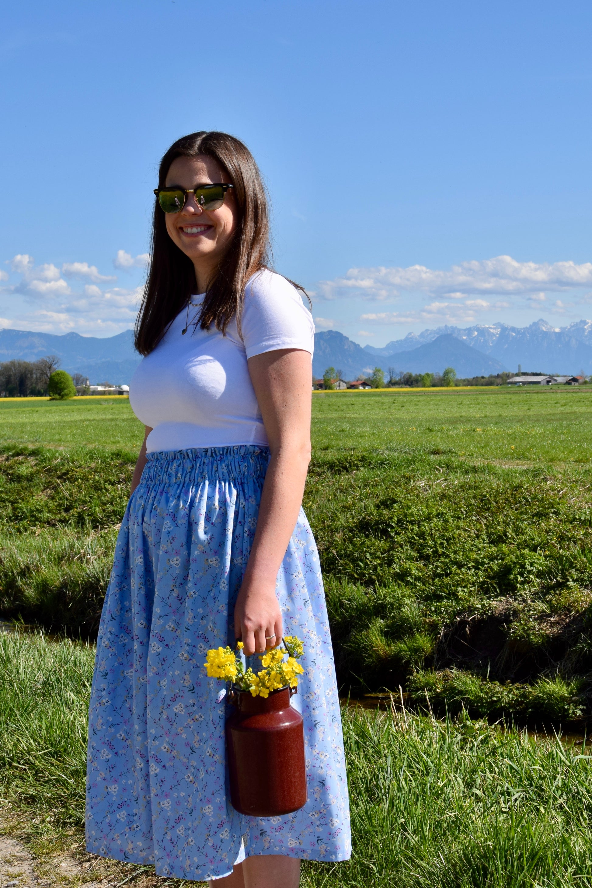 Frau vor Feld mit Rock und Blumen