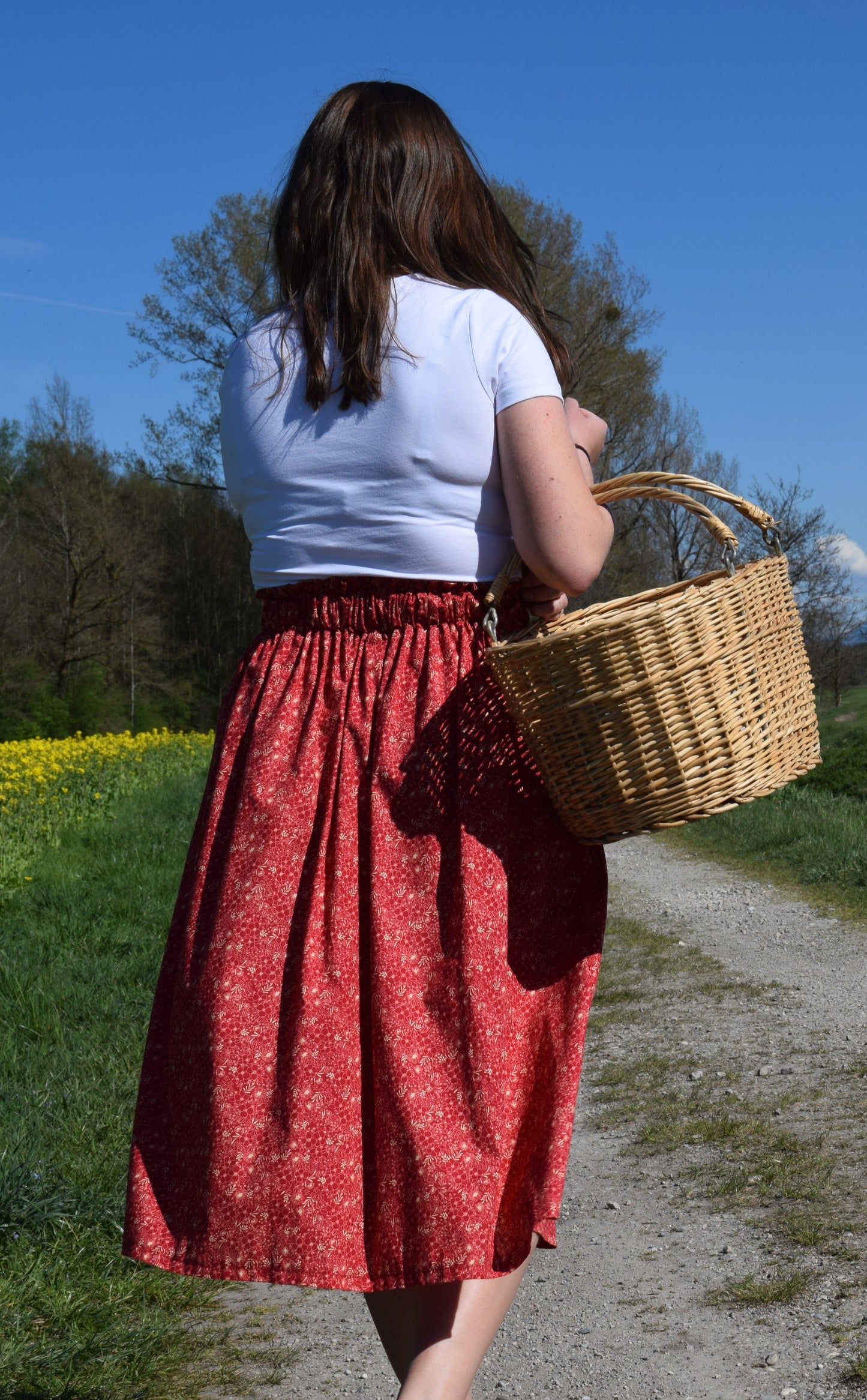 Frau mit roten Rock und Korb auf Weg