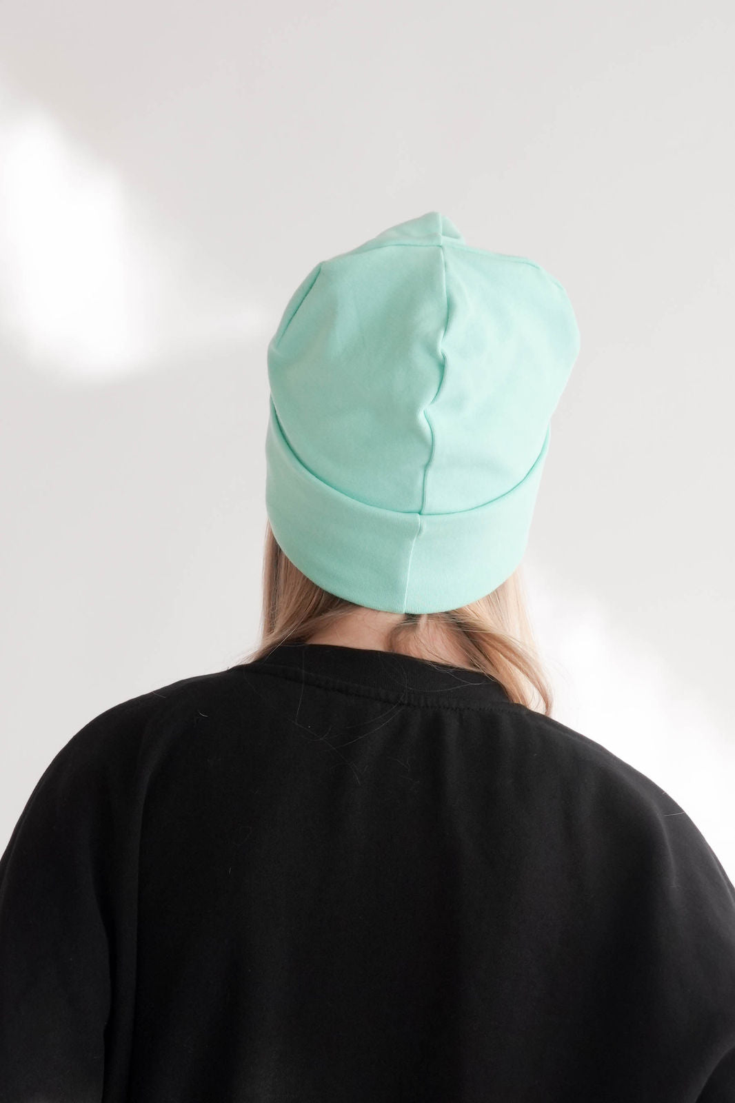 Frau mit mintfarbiger Mütze Hinteransicht 
